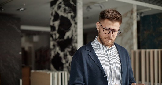 Young founder in glasses looking down at a phone in a modern office